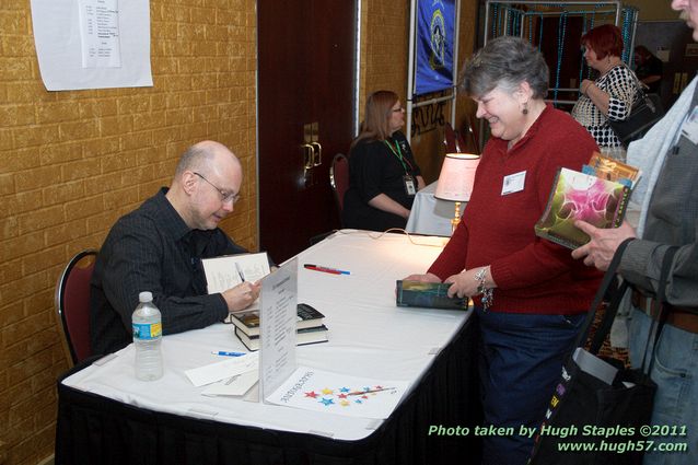 Guest of Honor Robert J. Sawyer signs books at the Autograph Table